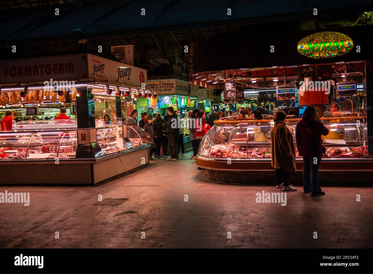 Barcelona,Spain-February 21,2023 Customers walk at night among brightly lit market stalls in la Boqueria Market Stock Photo