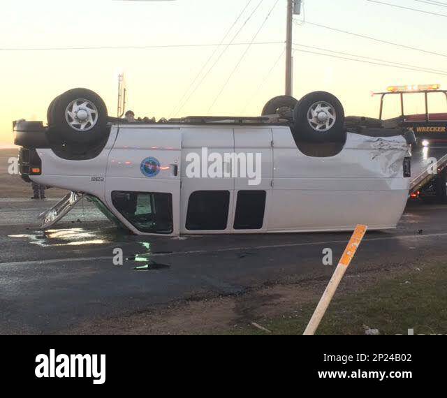 A towing wrecker prepares to move a prisoner transport vehicle that rolled over along East