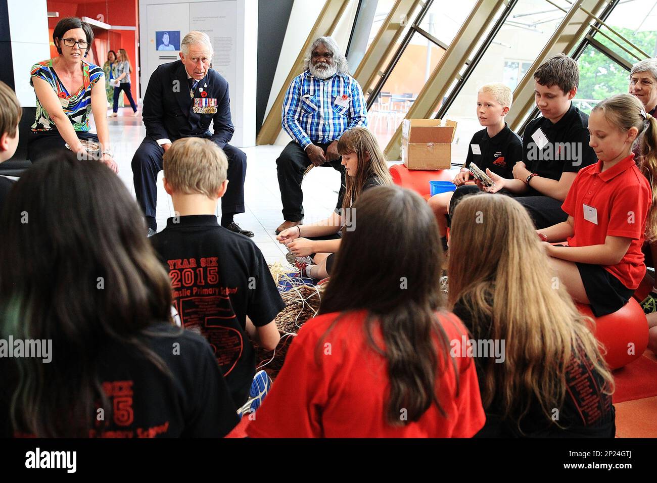 Britain's Prince Charles, second from left at top, speaks with children who are doing a craft with traditional and master basket maker Abe Muriata, top right, from the Girramay aboriginal tribe during a visit to the National Museum of Australia in Canberra, Australia, Wednesday, Nov. 11, 2015. Prince Charles and his wife Camilla, the Duchess of Cornwall, are on a six-day visit to Australia. (Stefan Postles/Pool via AP) Stock Photo