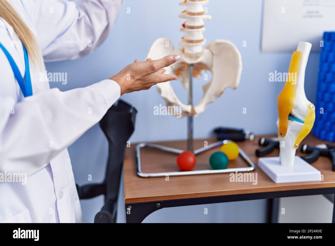 Young blonde woman wearing physiotherpist uniform pointing to