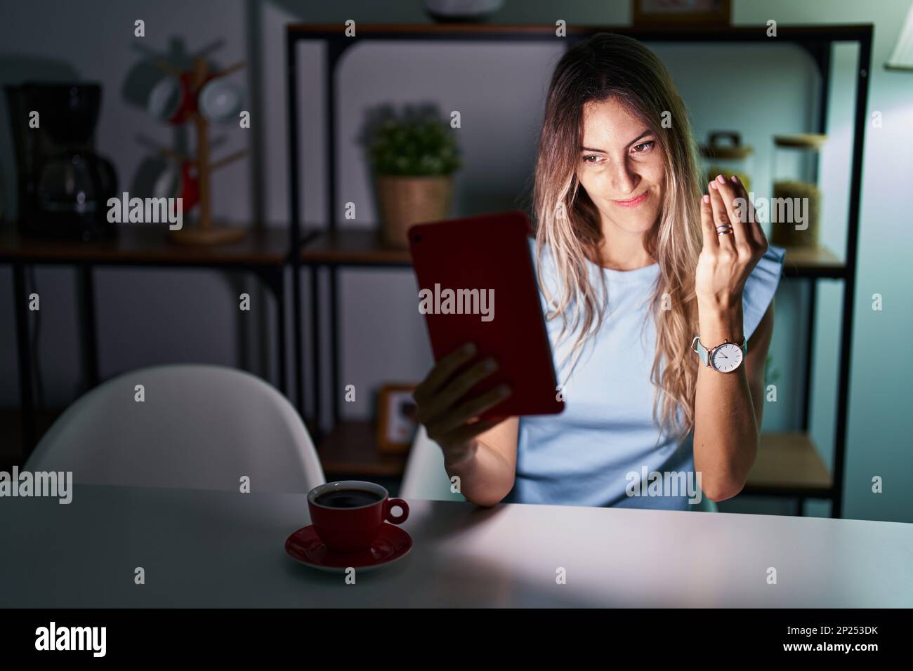 Young hispanic woman using touchpad sitting on the table at night doing ...