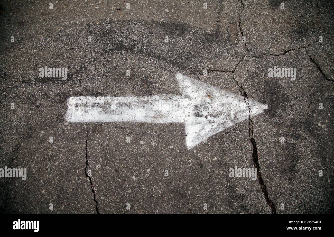 White arrow on the ground pointing right to the future. Asphalt painted ...