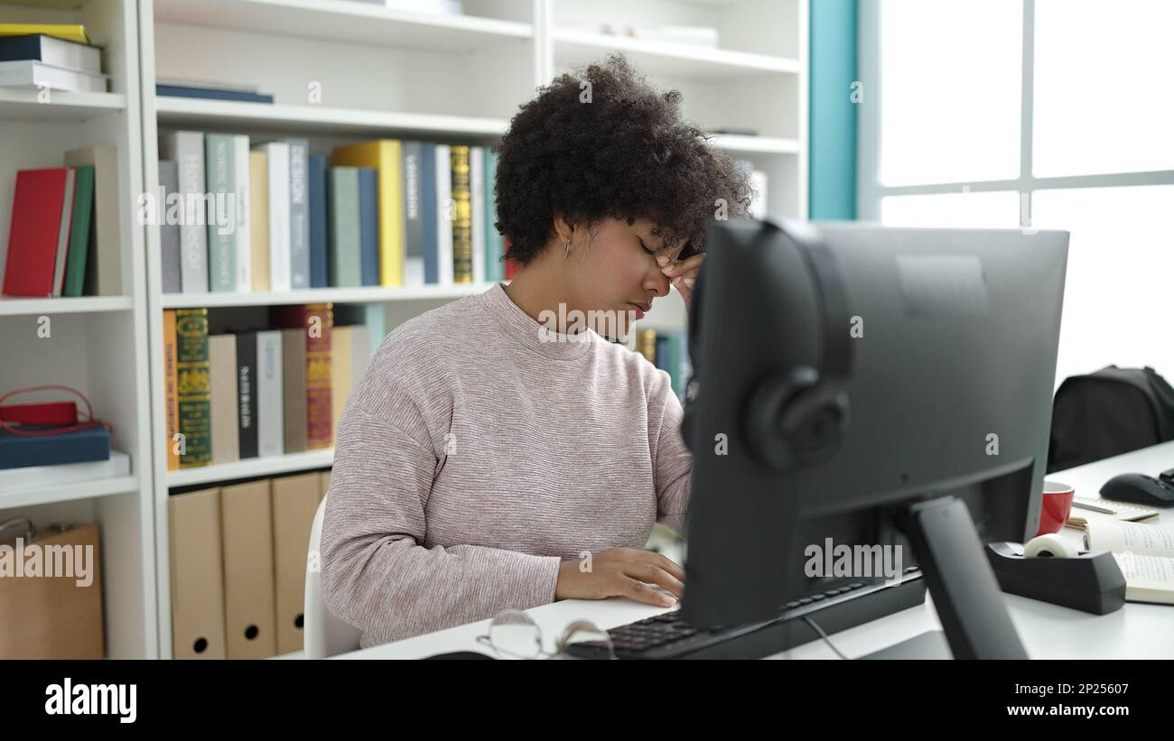 Young african american woman student using computer stressed at ...