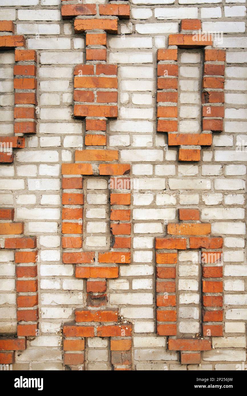 Decorative brickwork in a brick house wall. Orange geometric pattern on a gray background Stock Photo