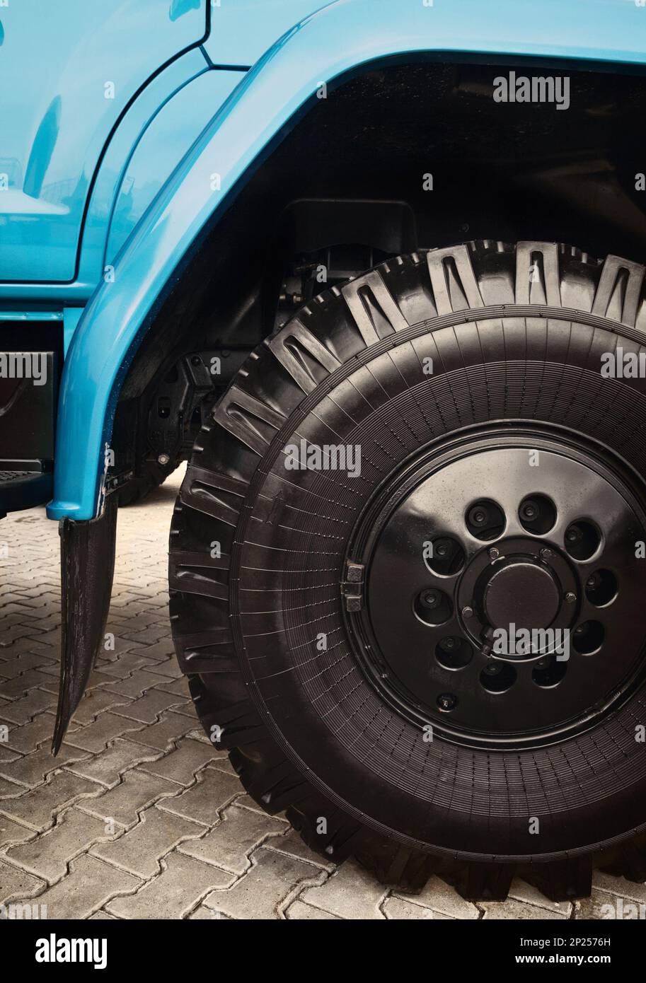Big heavy truck wheel close-up. Black and blue tipper detail background Stock Photo