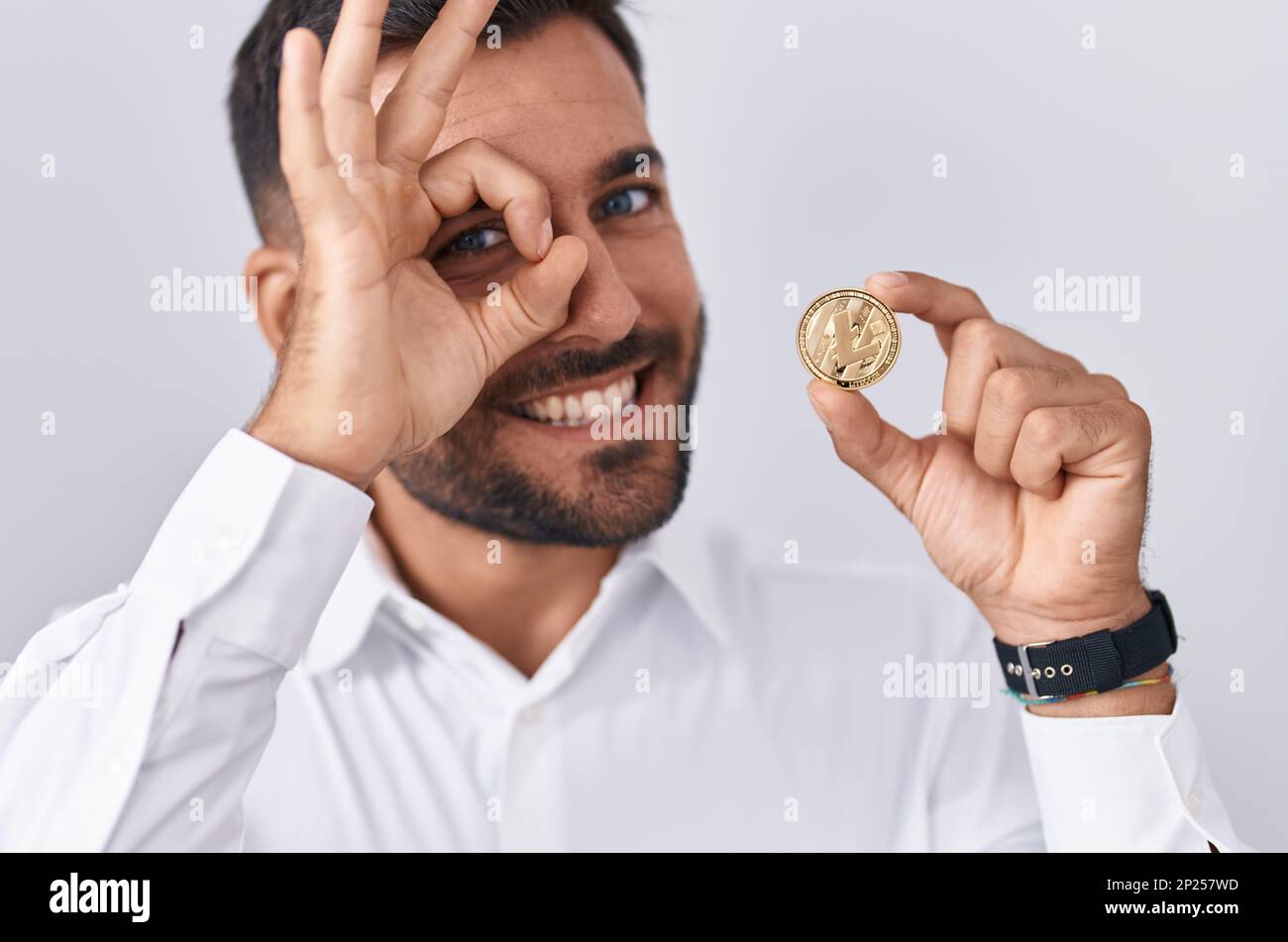 Handsome hispanic man holding litecoin cryptocurrency coin smiling happy  doing ok sign with hand on eye looking through fingers Stock Photo - Alamy