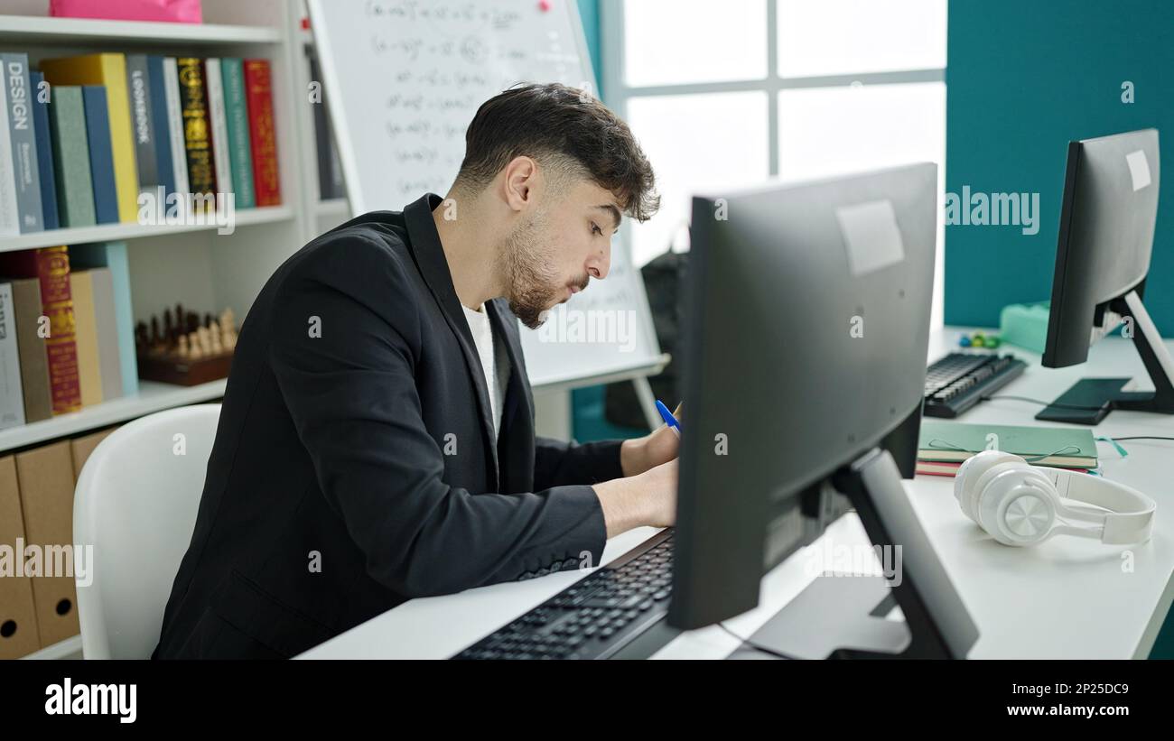 Young arab man student using computer writing on notebook at university ...