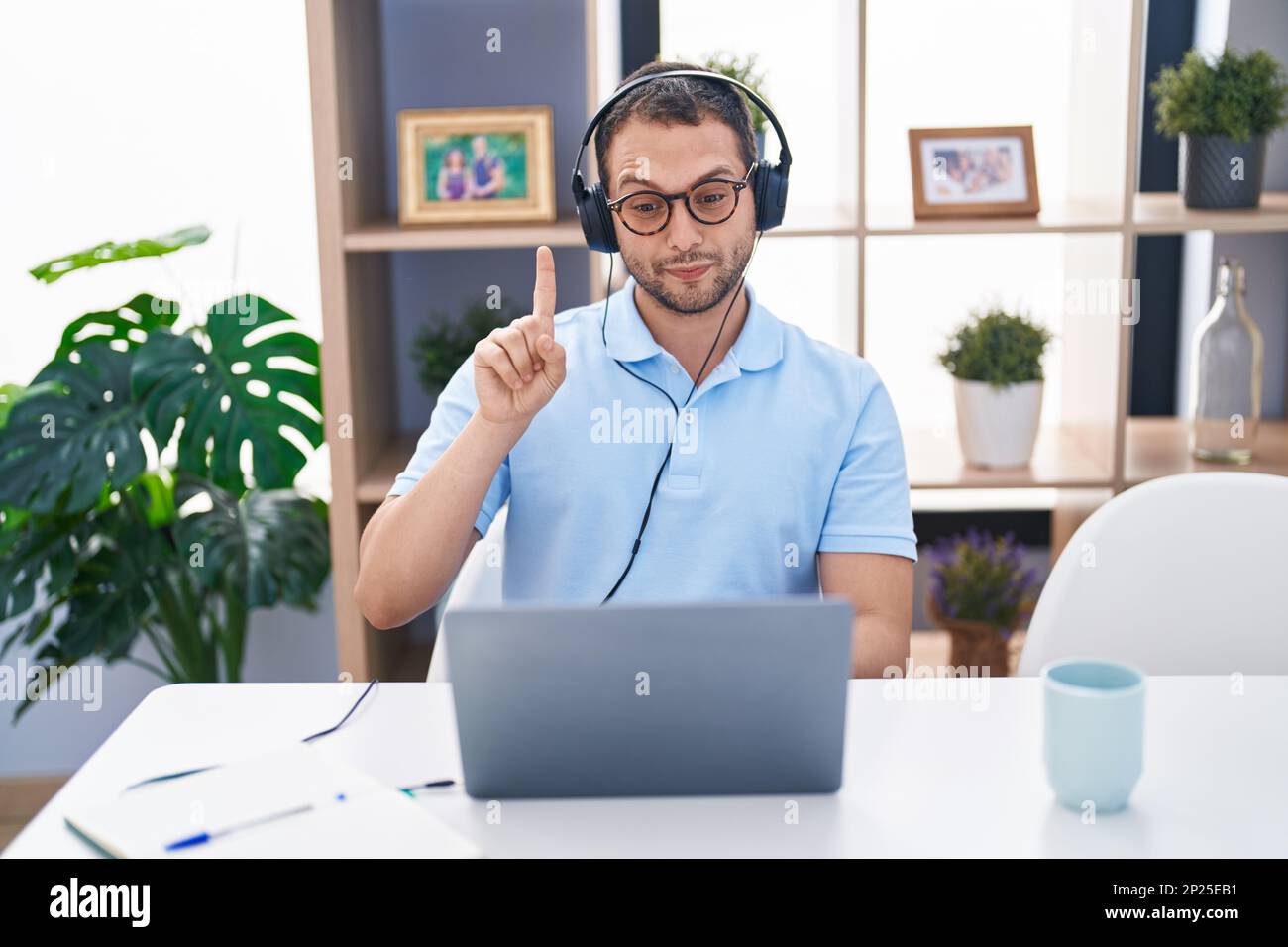 Hispanic Man Using Computer Hispanic man working using computer laptop wearing headphones smiling ...