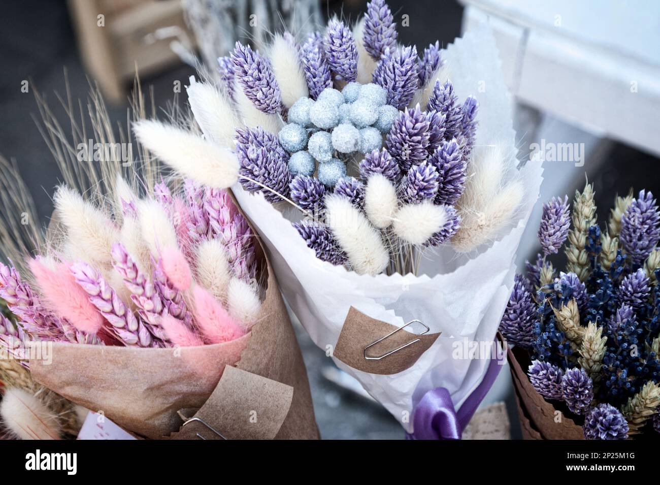 Dry herbs colorful purple and pink bouquets at flower shop. Beautiful bundles of pink and blue dried spikelets at a market - tinted lavender, canary g Stock Photo