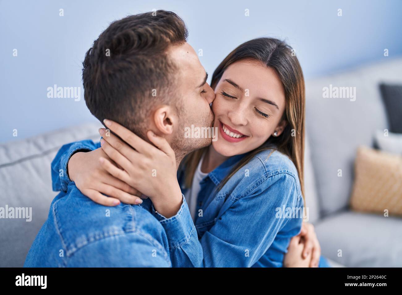 Man and woman couple sitting on sofa hugging each other and kissing at ...