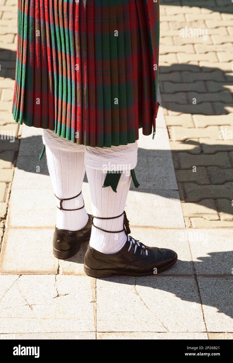 Red and green tartan Scottish kilt. Highlander wearing Scotland traditional clothes. Bagpiper uniform - skirt and knee socks Stock Photo
