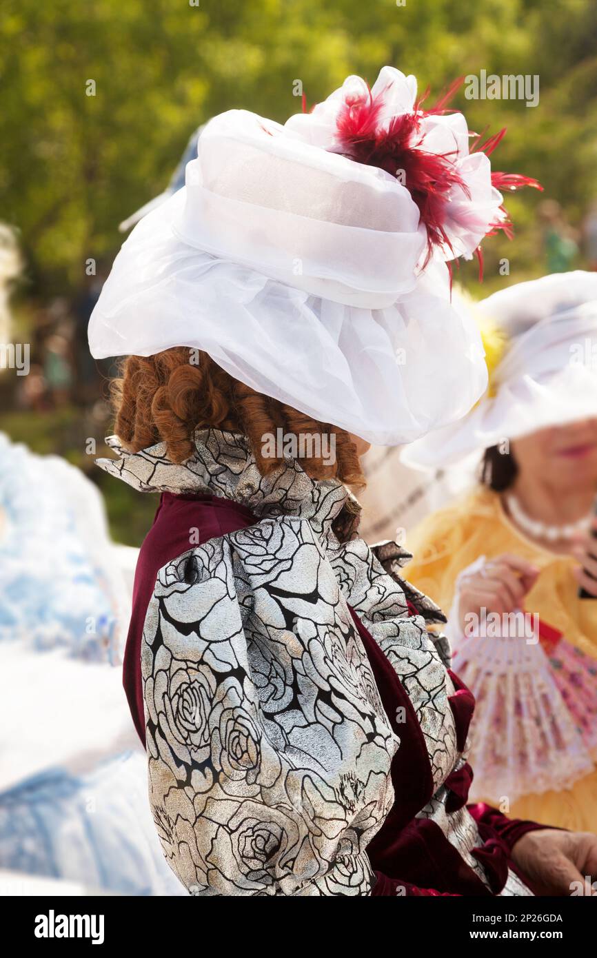 Elderly lady wearing a medieval formal dress and a hat. Mysterious old woman hiding her face. Historical female costume in a role-play Stock Photo