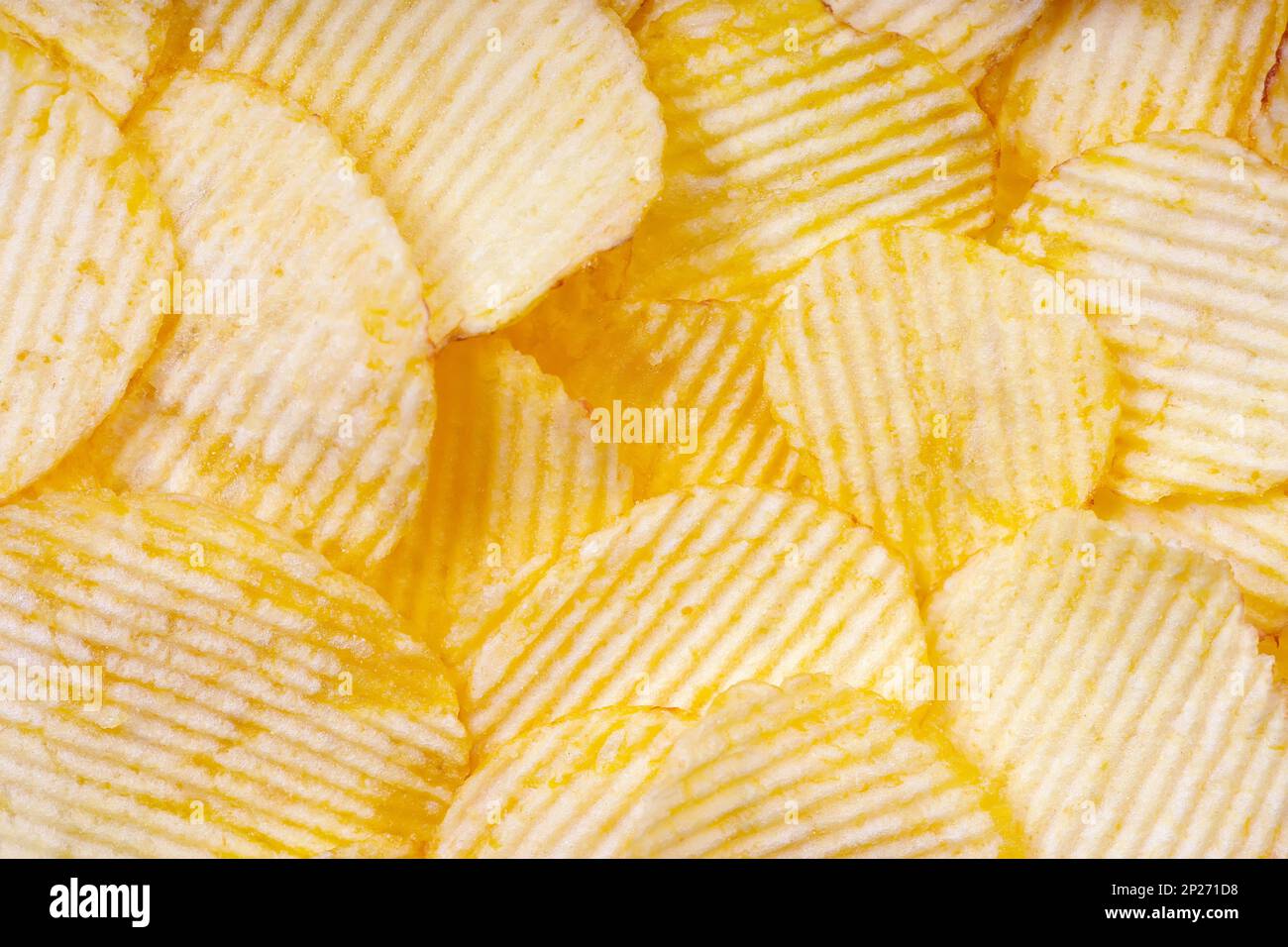 Yellow crispy ridged potato chips close up. Food background, banner