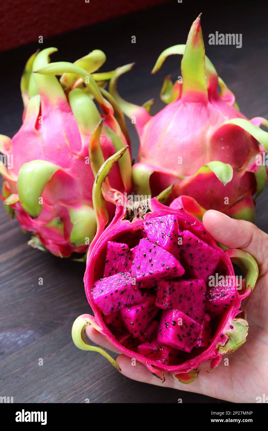 Diced Ripe Pink Pitaya or Red Flesh Dragon Fruit with Blurry Whole Fruits in the Backdrop Stock Photo