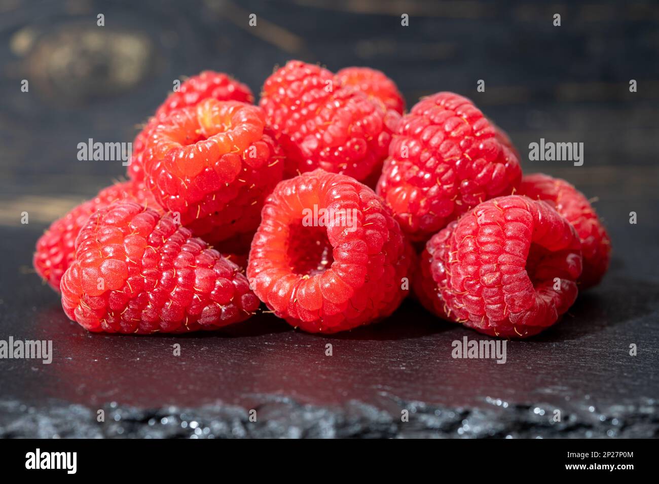 Fresh organic fruit - ripe red sweet raspberry on dark background close ...
