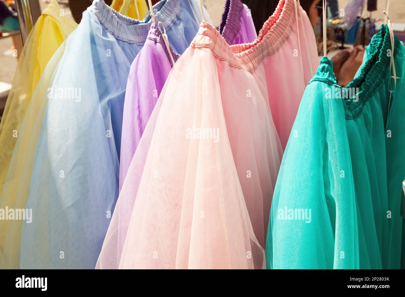 Row of hanging colorful gauze skirts at a clothing store. Brightly colored performance costumes background Stock Photo