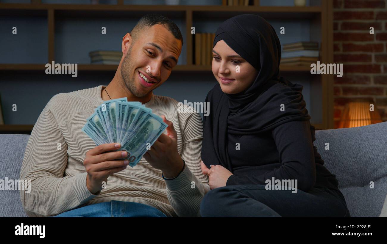 Rich muslim woman and african american man owners hold cash dollars