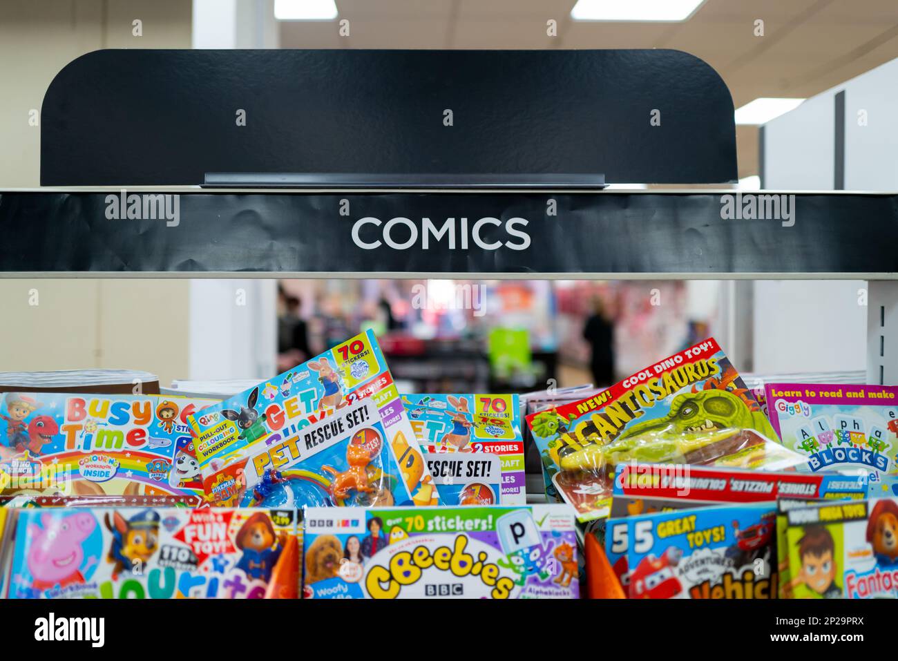 Shallow focus of the Comic banner seen within a popular high street newsagent. A selection of children comics can be seen stacked on the shelf. Stock Photo