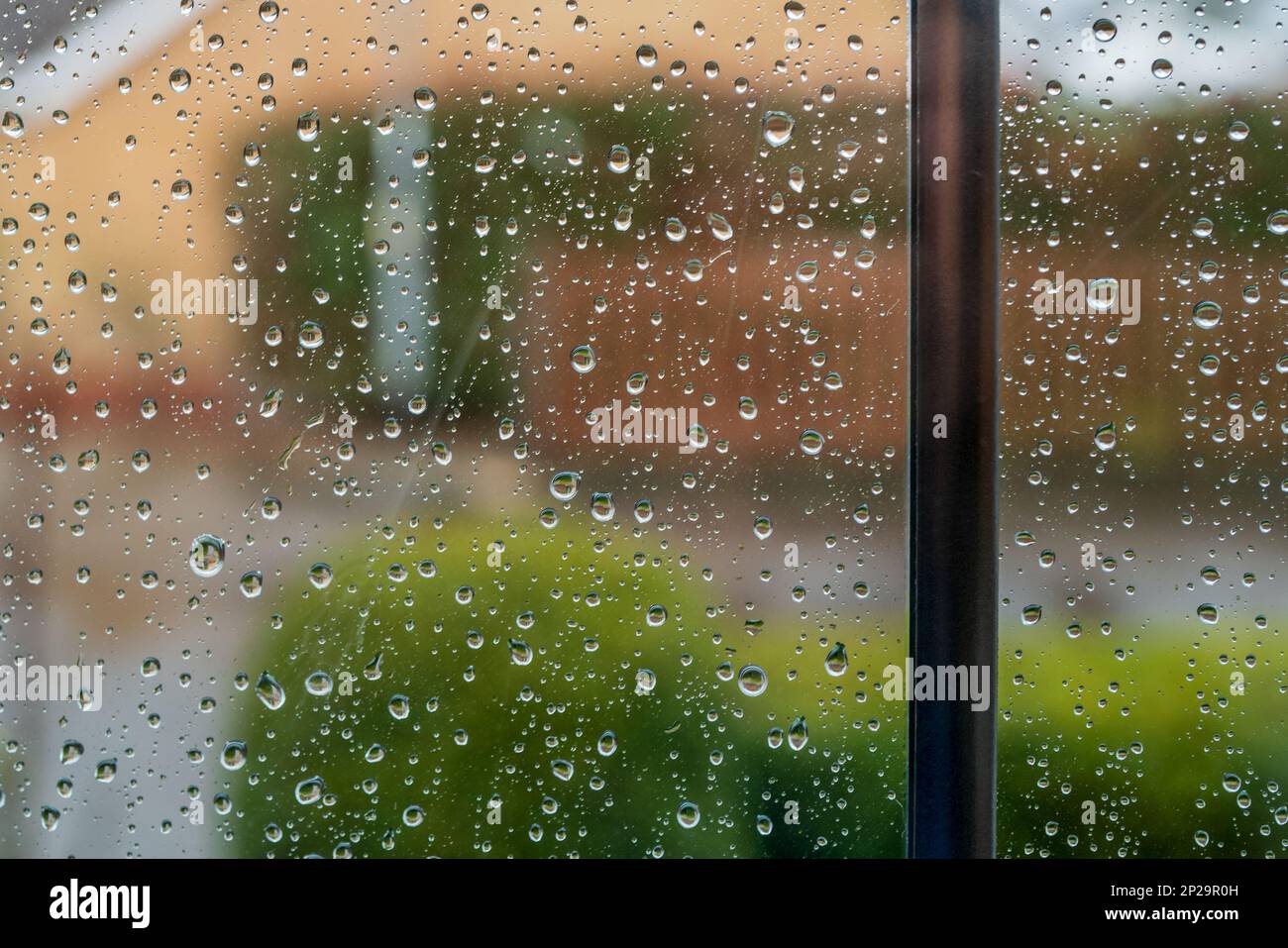 Shallow focus of fresh raindrops seen on a newly installed, double glazed window. Looking out to a private cut de sac. Stock Photo