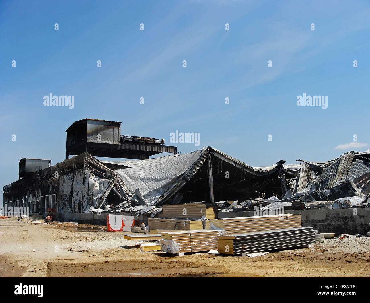 Consequences of a warehouse fire. The metal structure building collapsed from the fire, the columns and walls were burnt. Stock Photo