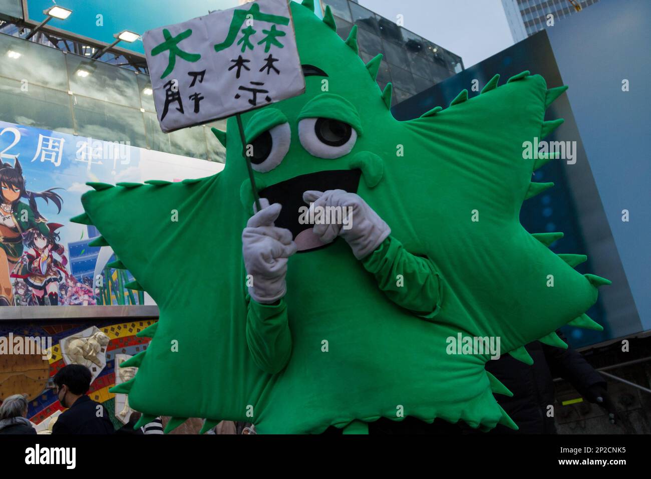 A cannabisleaf shaped mascot holds a placard during a promarijuana