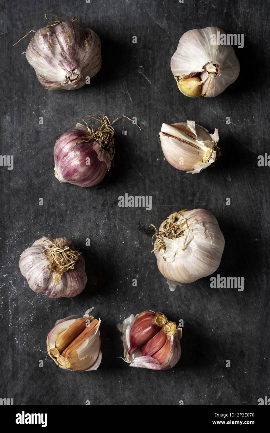Fresh garlic bulbs and cloves grouped on black background. Flat lay ...