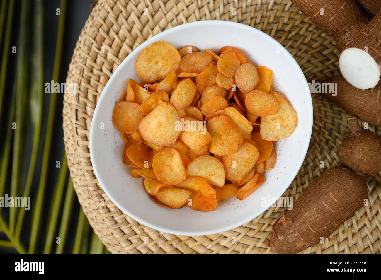 Indonesia Cassava chips in bowl and tapioca root. Popular hot spicy yuca chips. View from above. Stock Photo