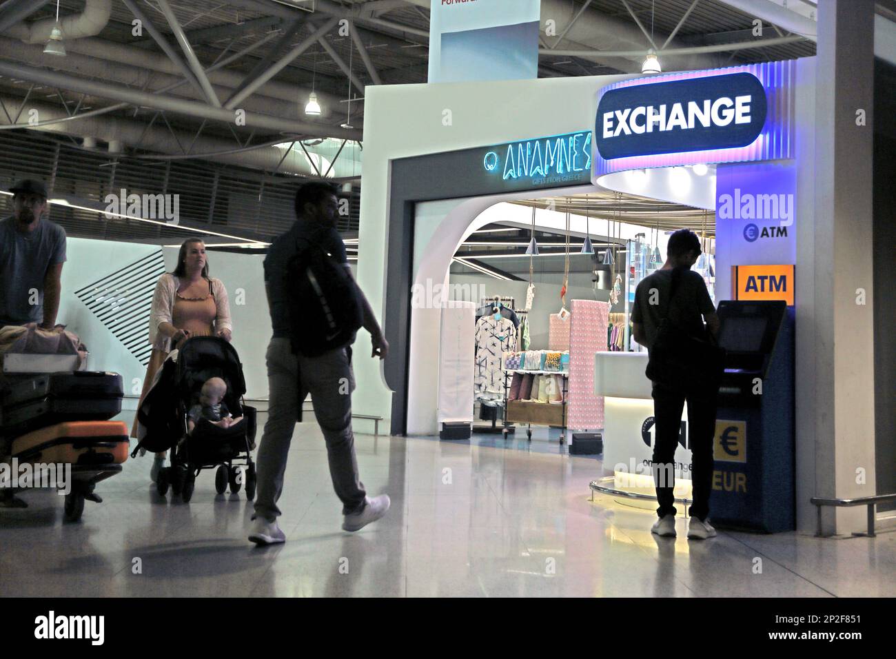 Athens Greece Athens International Airport (AIA) Eleftherios Venizelos Family Pushing Luggage on Airport Trolley by ATM and Currency Exchange Machine Stock Photo