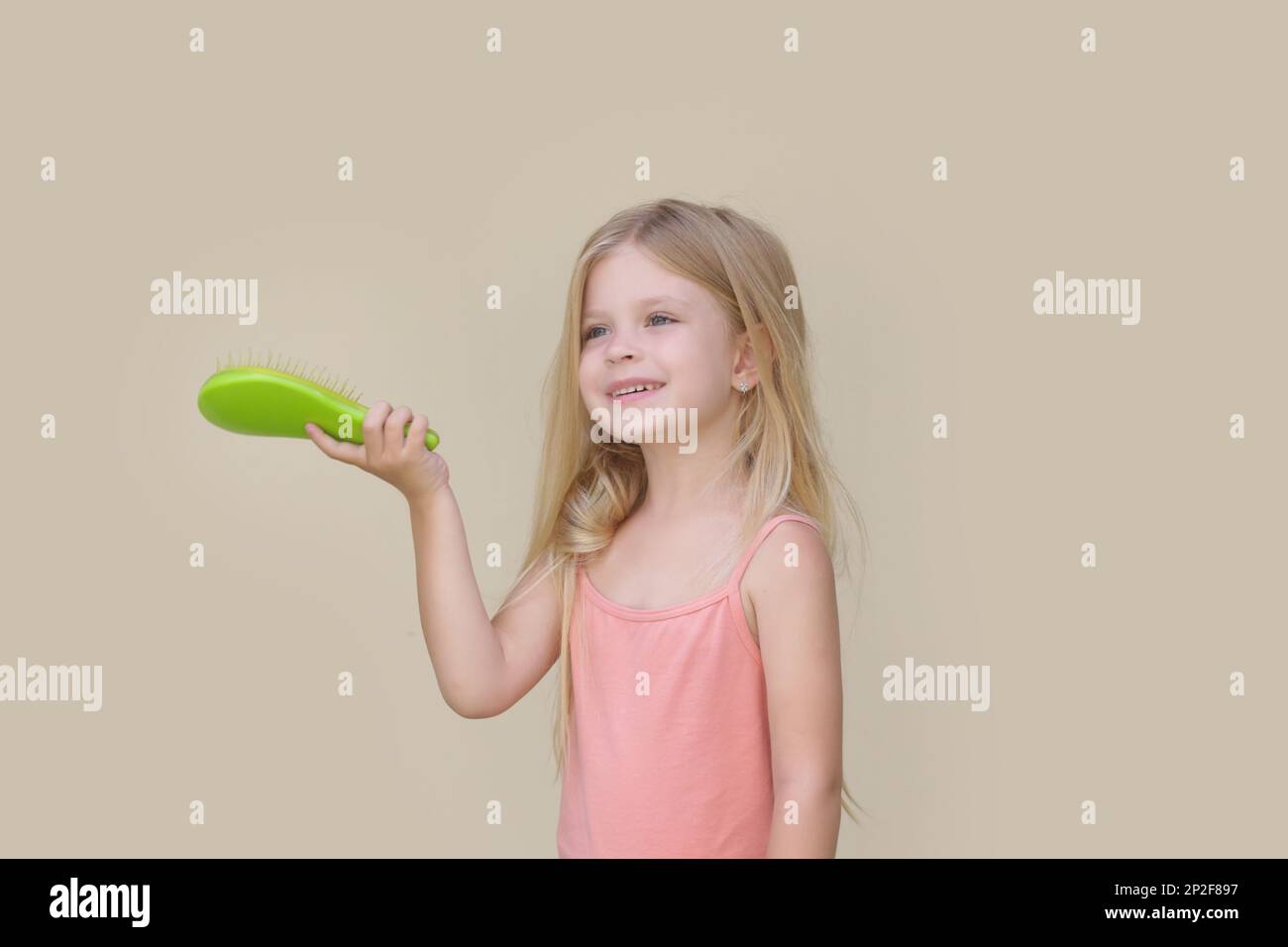 Candid portrait of cute little girl combing her long hair with detangler brush Stock Photo