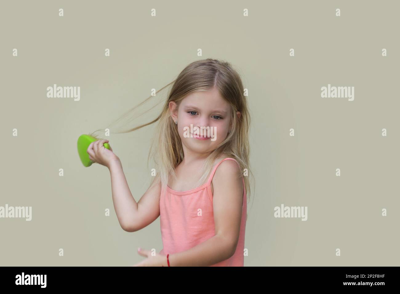 Candid portrait of cute little girl combing her long hair with detangler brush Stock Photo