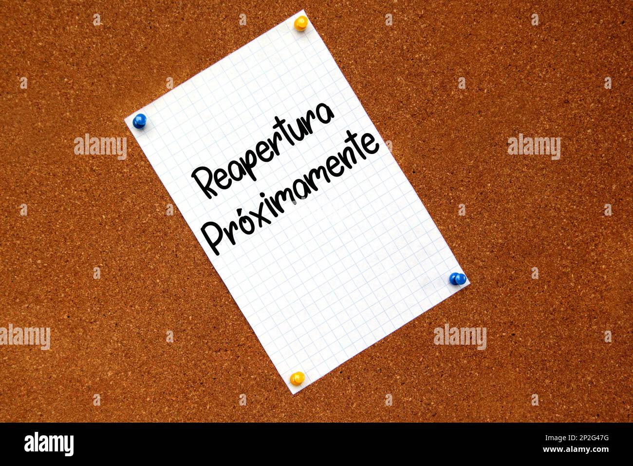 White note on cork board with message in Spanish language "Reopening