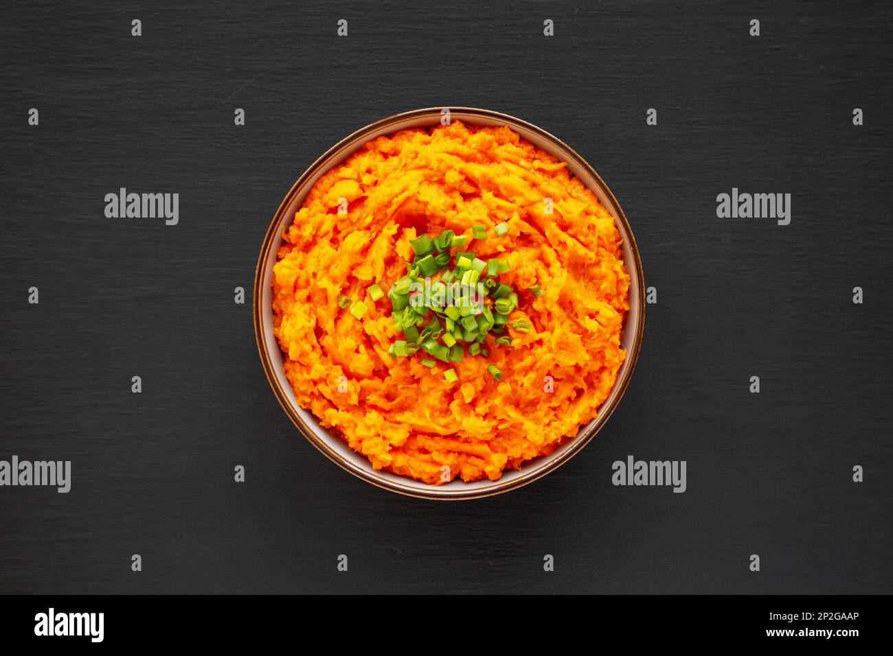 Homemade Creamy Mashed Sweet Potatoes with MIlk and Butter in a Bowl on a black background, top view. Stock Photo