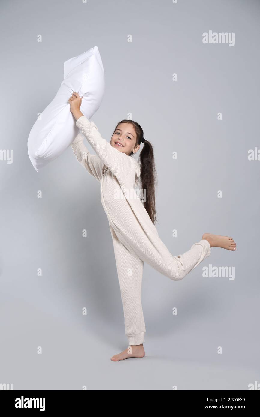 Cute girl in white pajamas with pillow on light grey background Stock ...