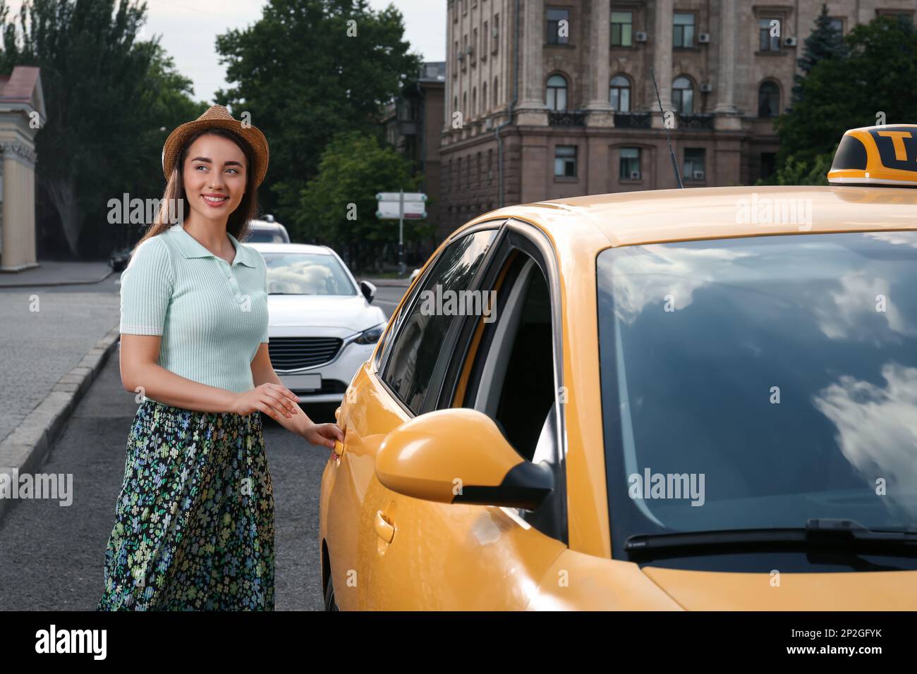 Beautiful young woman getting in taxi on city street Stock Photo