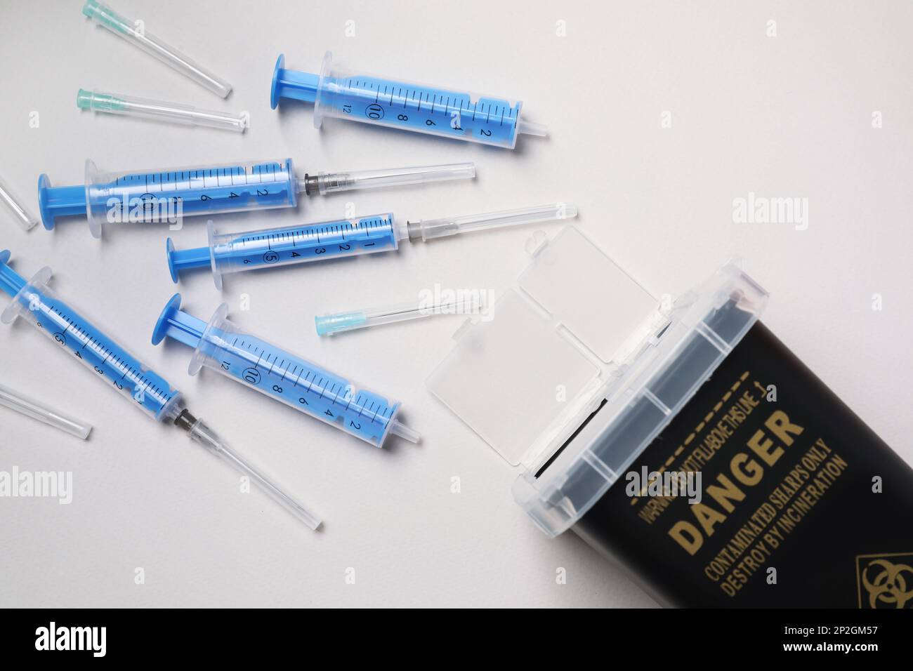 Disposable Syringes Needles And Sharps Container On Light Background disposable-syringes-needles-and-sharps-container-on-light-background