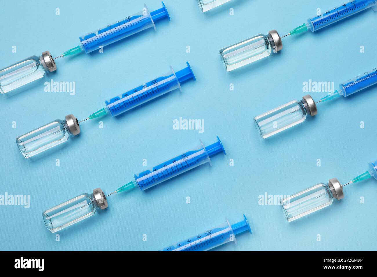 Disposable syringes with needles and vials on light blue background ...