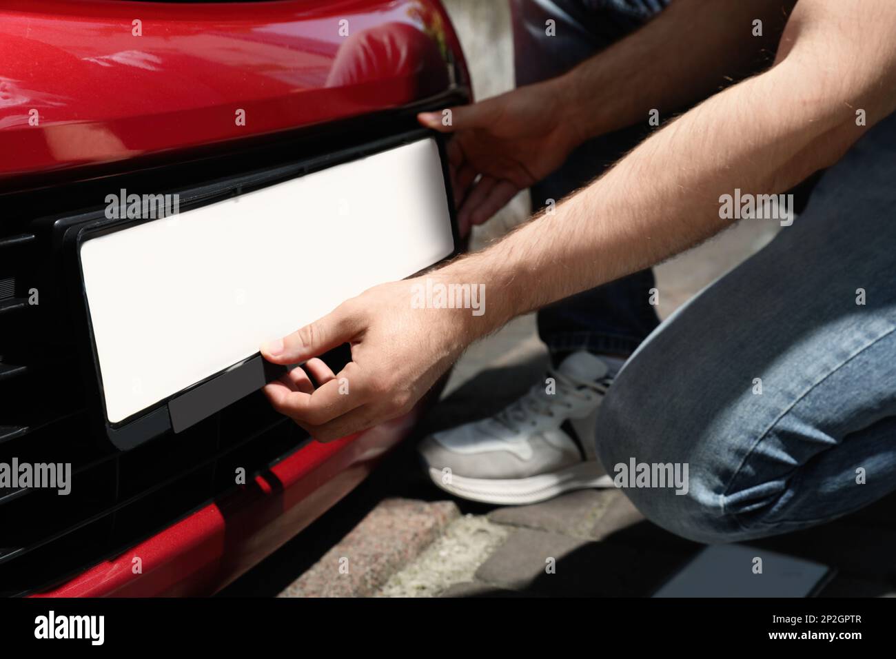 Man installing vehicle registration plate outdoors, closeup Stock Photo