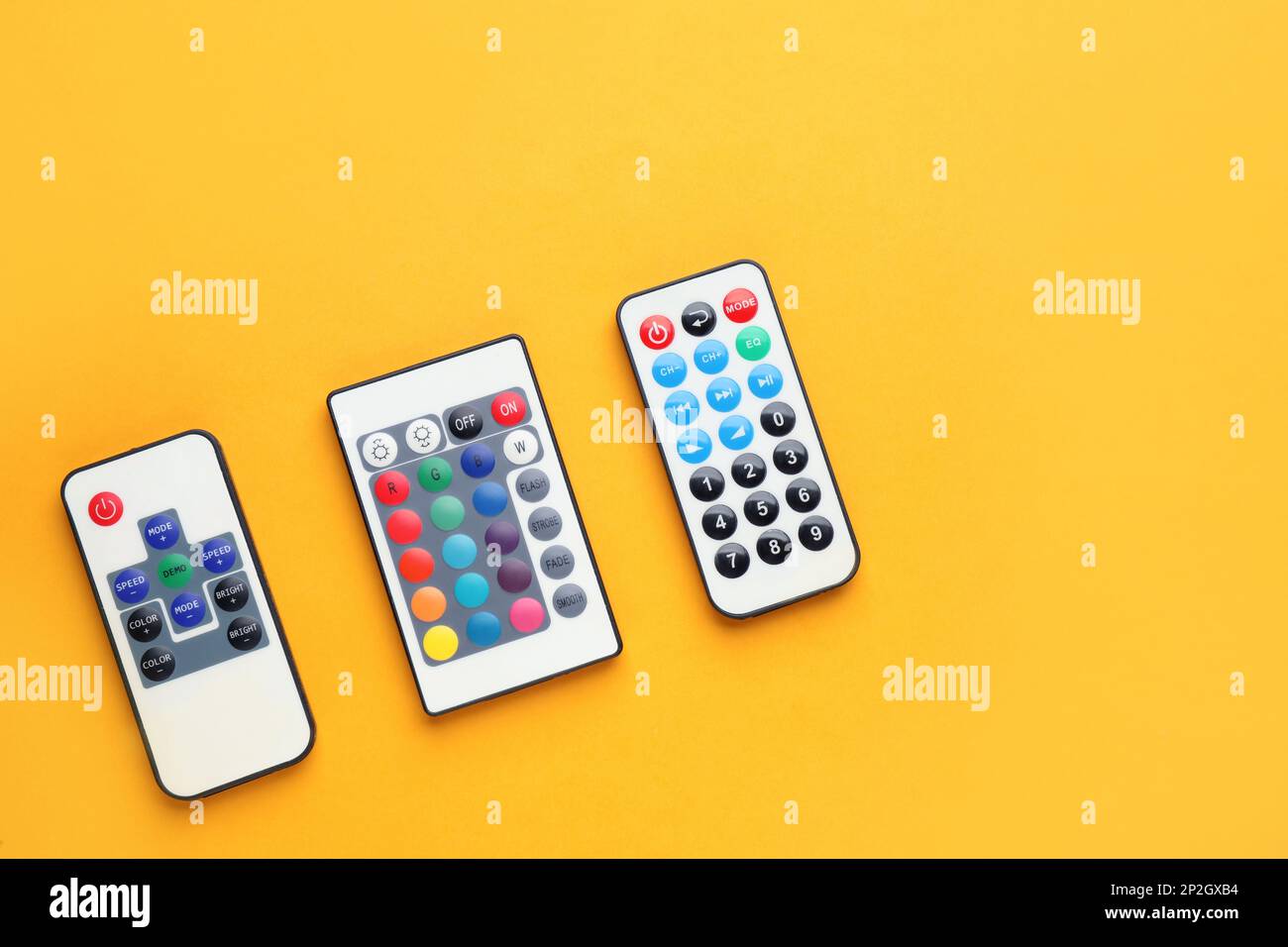 Remote controls on yellow background, flat lay. Space for text Stock Photo