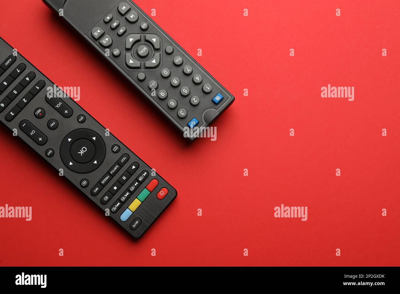 Remote controls on red background, flat lay. Space for text Stock Photo