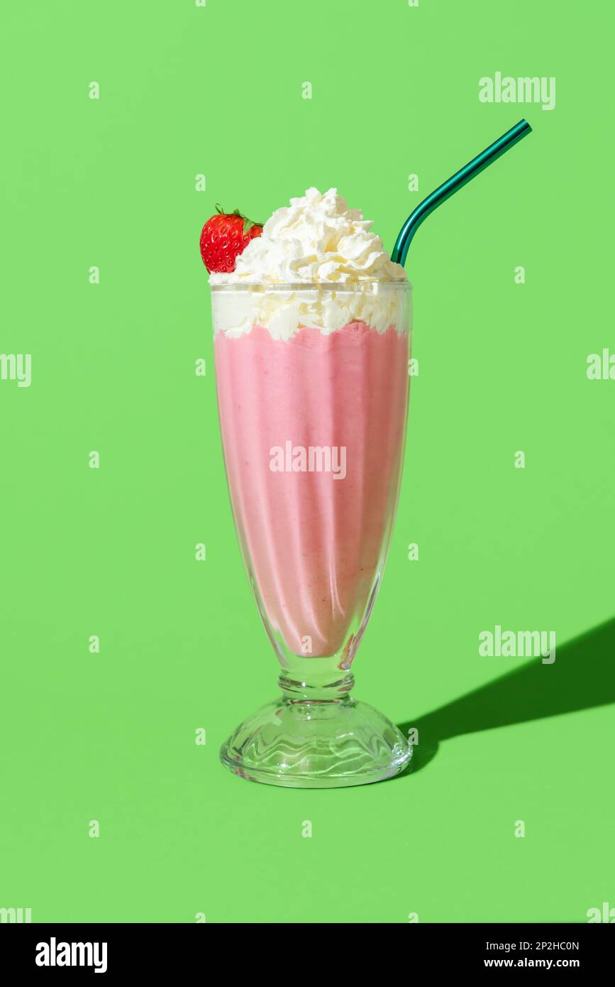 Strawberry flavored milkshake in bright light, minimalist on a green