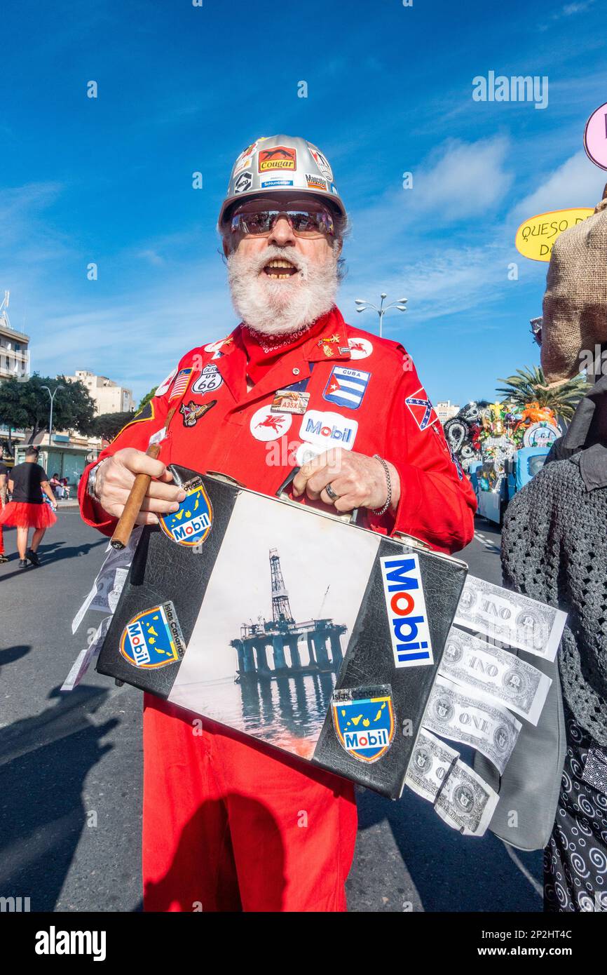 Man in fancy dress at Las Palmas carnaval dressed in red overall and carrying briefcase full of dollars. Oil industry profits, big bonus, bonuses, global warming...concept Stock Photo