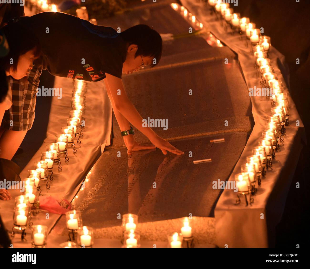 Bereaved family members pray in front of candles paying tribute to