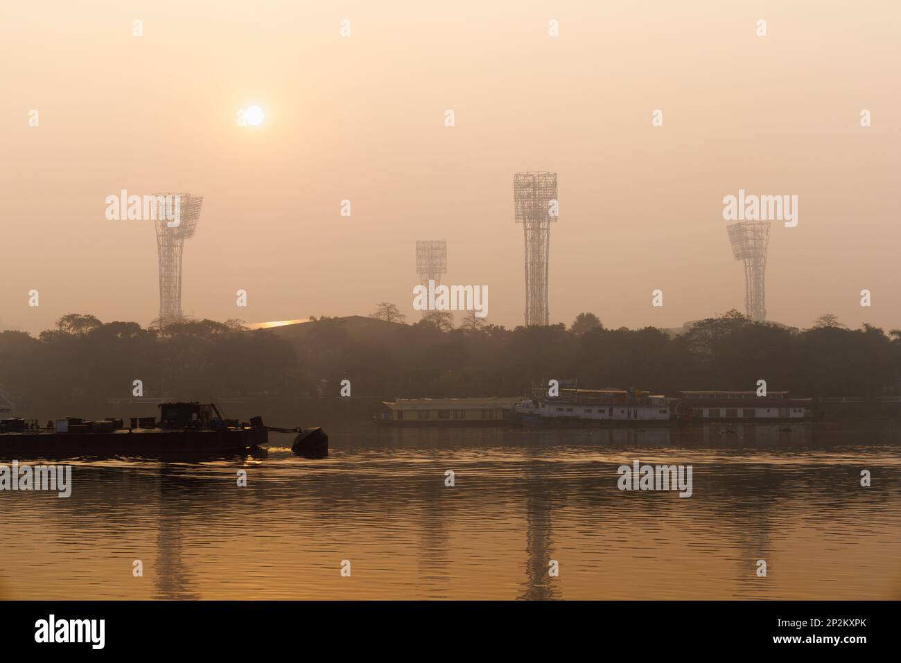 Sun rising in the smoggy atmosphere over the Hooghly River by Eden Gardens cricket stadium at Kolkata (Calcutta), capital city of West Bengal, India Stock Photo