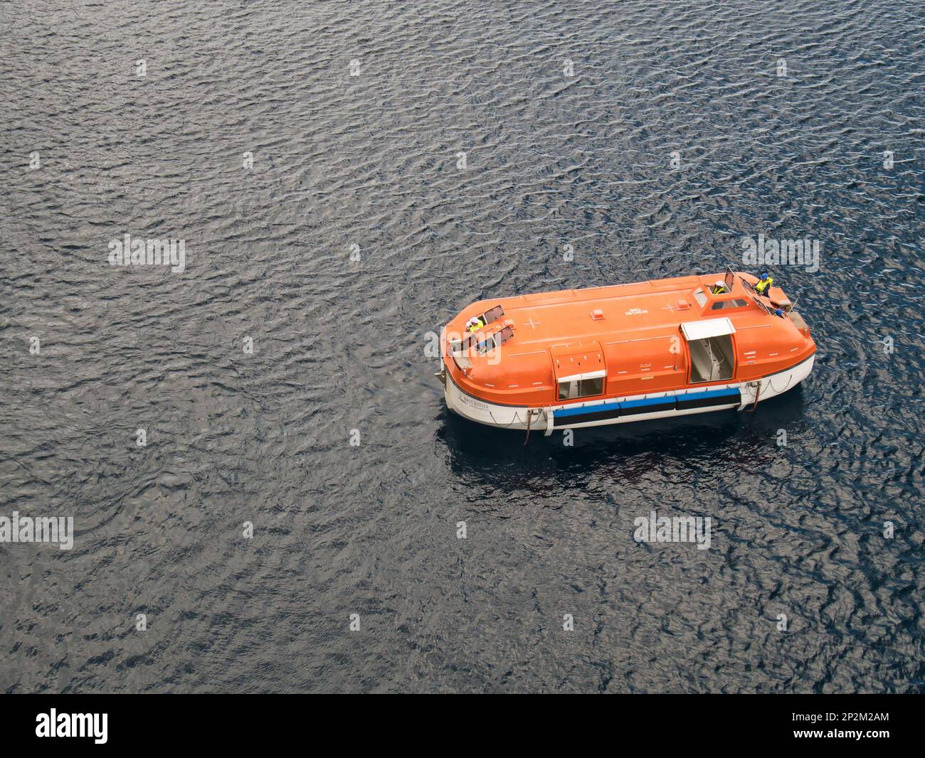 Orange lifeboat from the P and O cruise ship, MV Britannia practising an emergency drill in the Caribbean Sea Stock Photo