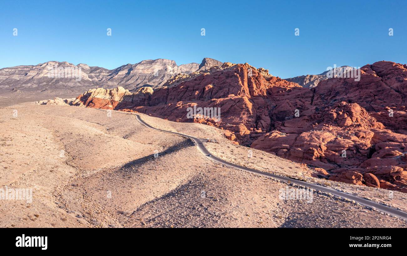 Red Rock Canyon in Las Vegas Nevada shows a lone, remote road along the vibrant mountainside where hiking activity is common and conservationists stri Stock Photo