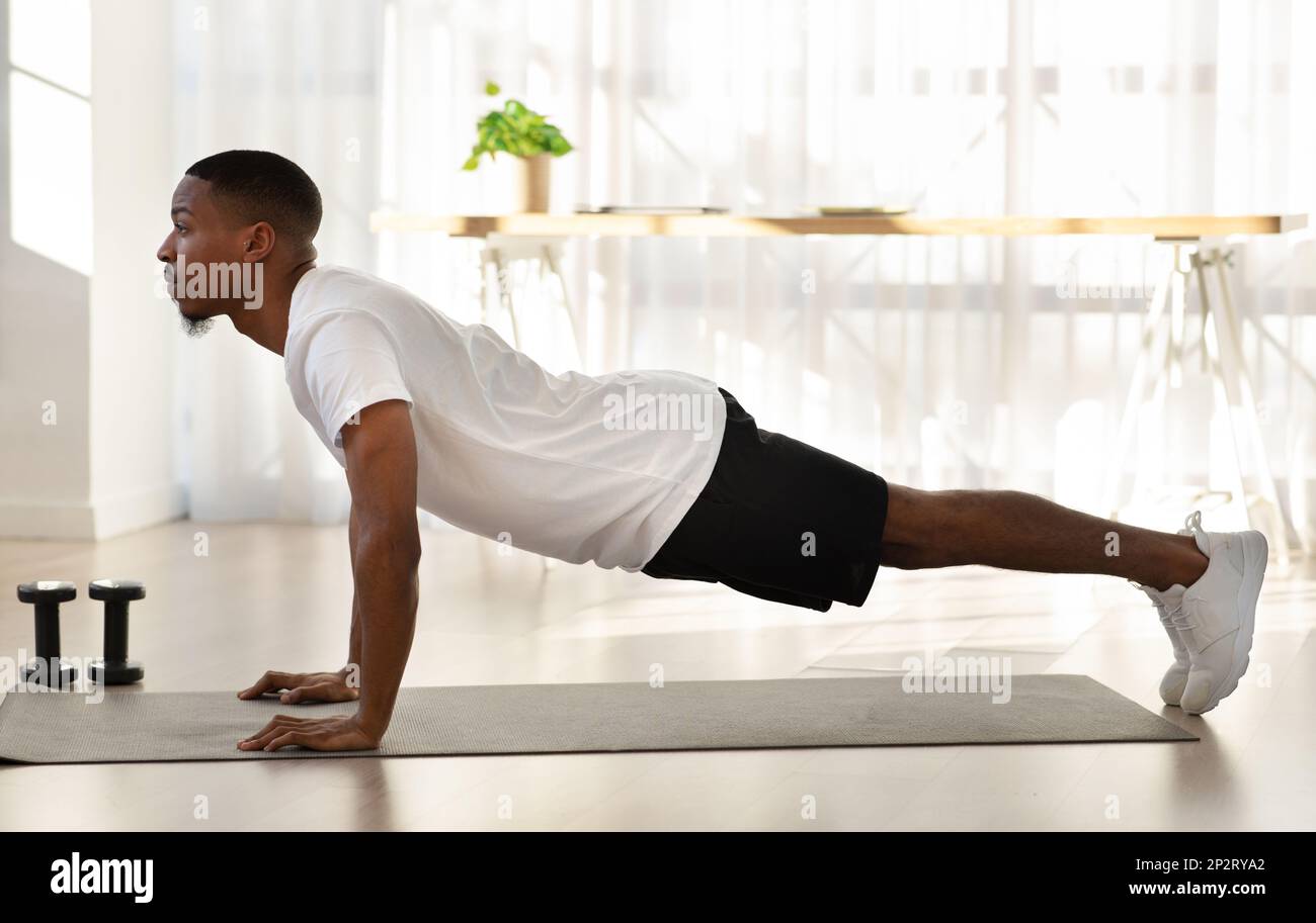 Athletic young black man doing workout at home, side view Stock Photo