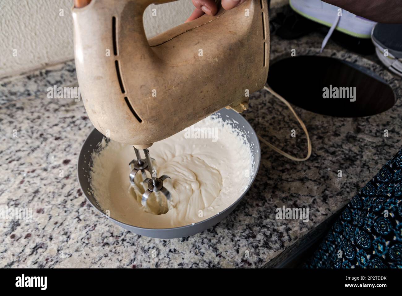 Electric mixer being used to prepare cheesecake ingredients. Family