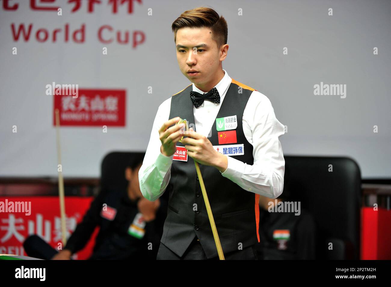 Xiao Guodong of China chalks his cue as he considers a shot against the Indian player during their first round match of the 2015 Snooker World Cup in Wuxi city, east Chinas