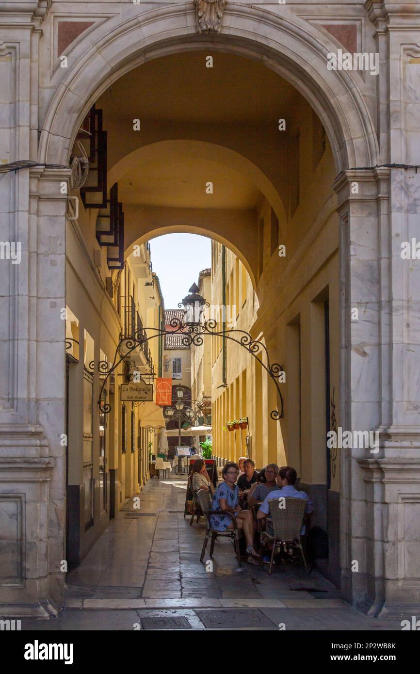 Malaga, Spain - June 18th 2018: People sat in a cafe in an alley. The city is the capital of a province with the same name Stock Photo