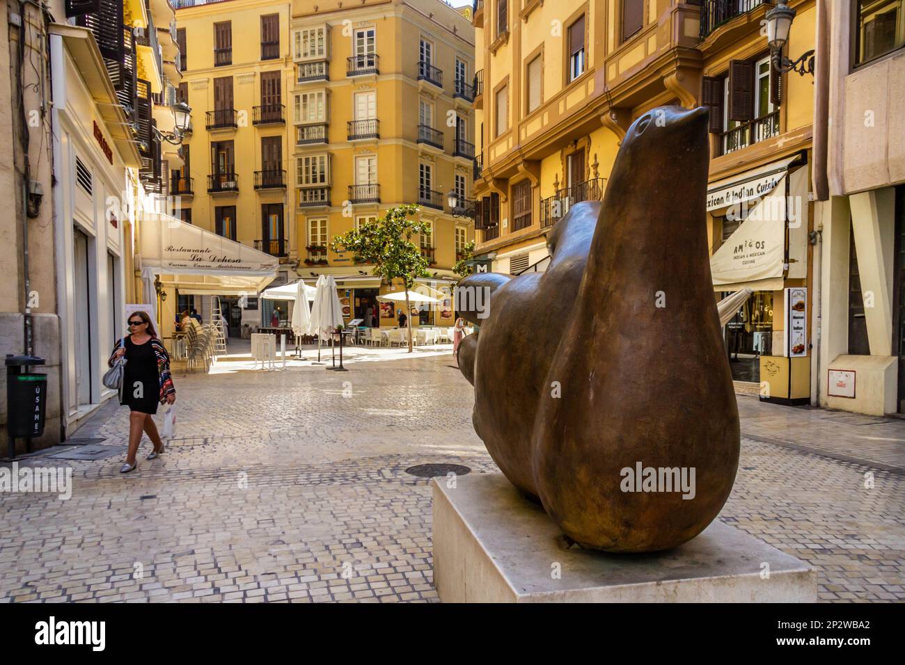Malaga, Spain - June 18th 2018: A woman walks past a bronze statue of a bird.. The city is the capital of a province with the same name Stock Photo
